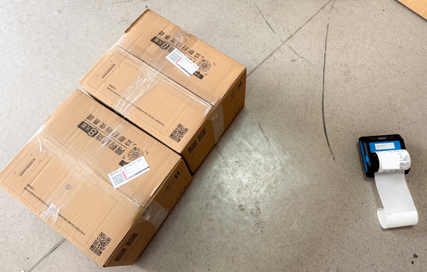 Shipping boxes and label printer on concrete floor.